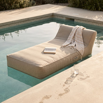 Poolboy Floata-Long in Natural beige by the pool, a towel left over it.