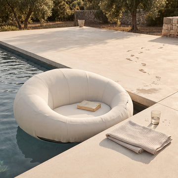 Poolboy Floata-Round in Cloud white at the pool edge, a book left on the seat.