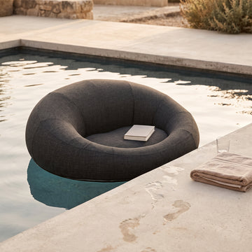 Poolboy Floata-Round in Dusk charcoal at the pool edge, a book left on the seat.
