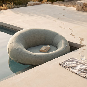 Poolboy Floata-Round in Mist grey at the pool edge, a book left on the seat.