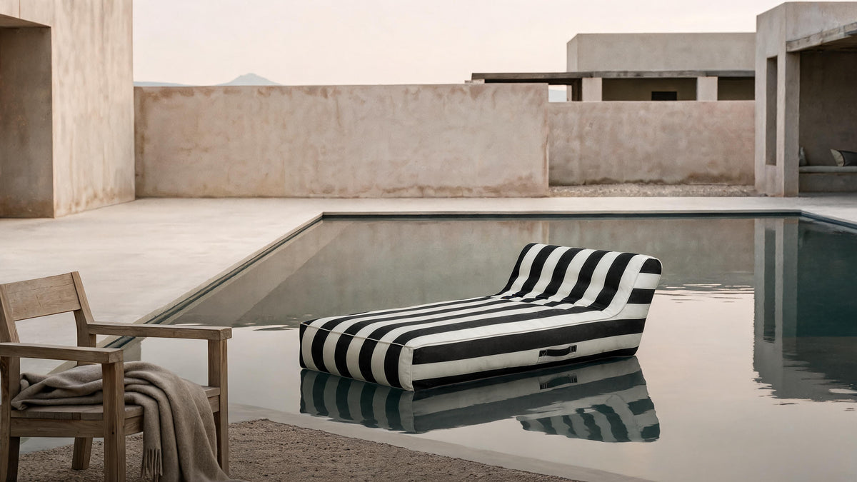 Poolboy Floata-Long in Black and White stripe floating on a still courtyard pool.