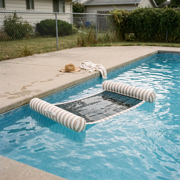 Poolboy Sinka-Bit in Khaki and White stripe in the pool, a towel left on the paving.